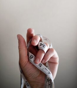 person's left hand wrapped by tape measure
